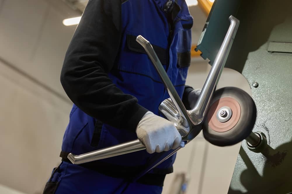 Das Aluminium-Untergestell eines Stuhls wird neu aufpoliert